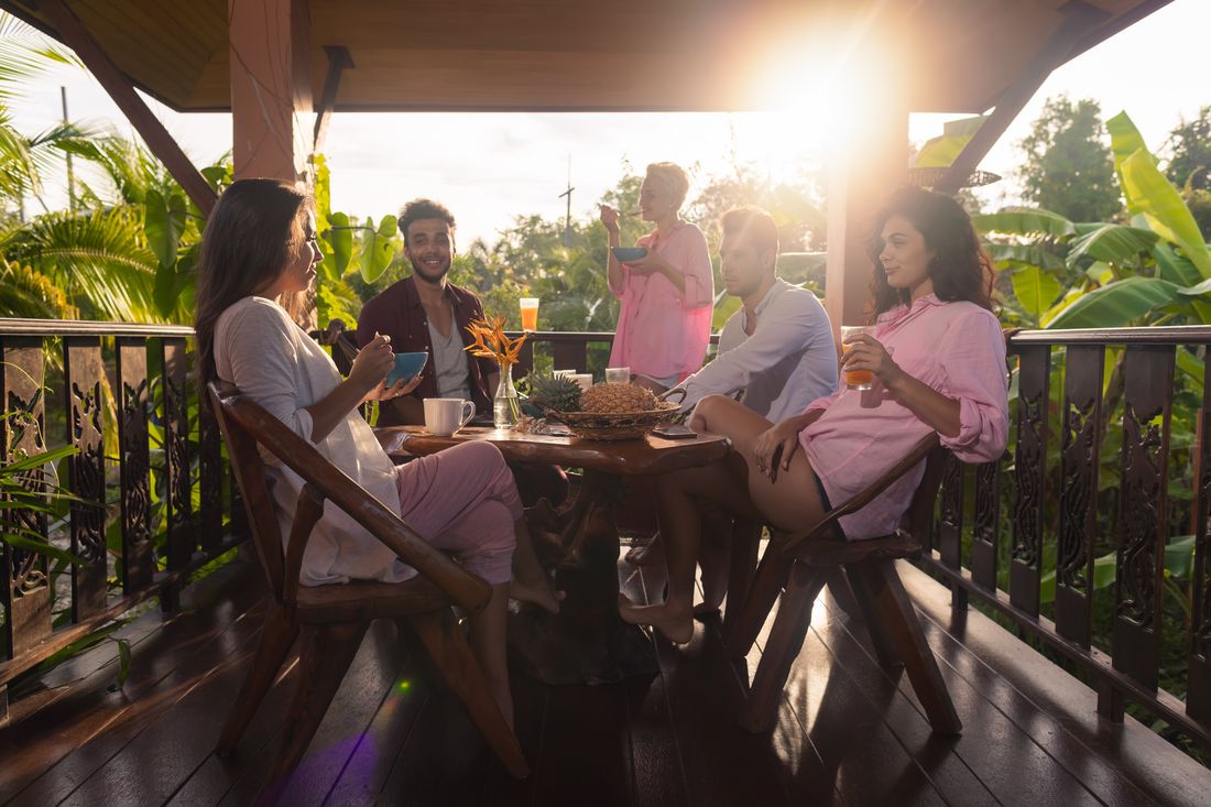 Friends talking over breakfast on a tropical terrace