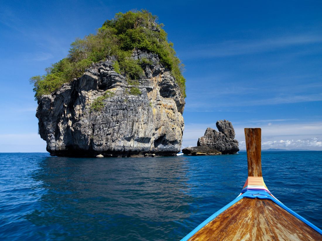 A longtail boat heading towards a limestone island